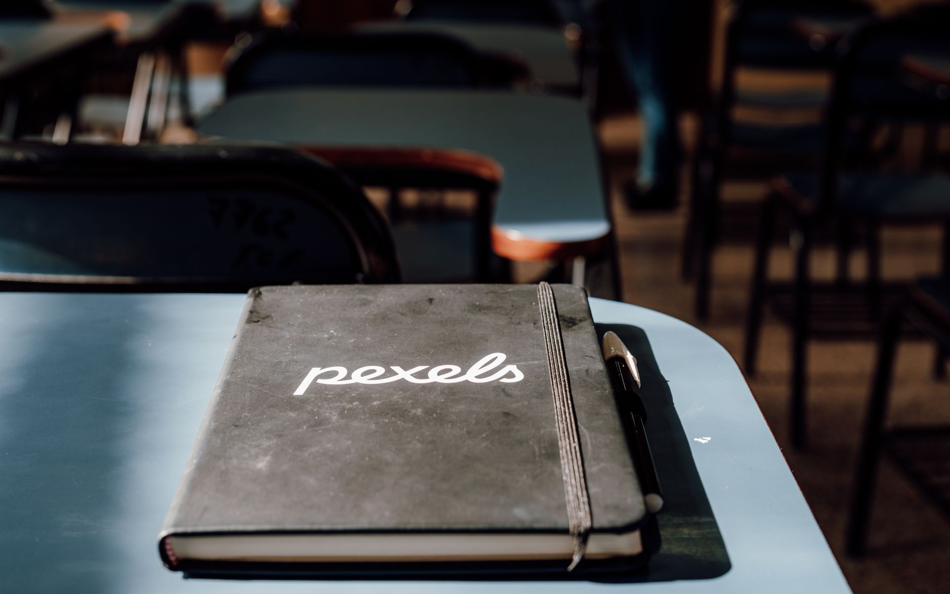 A close-up of a notebook and pen in a classroom setting.